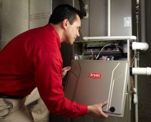 A man in a red shirt is working on an air conditioner.