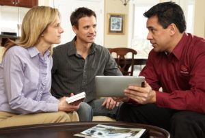 A man and a woman are sitting on a couch looking at a tablet.