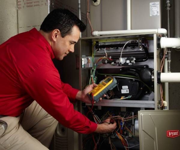 A man in a red shirt is working on an air conditioner
