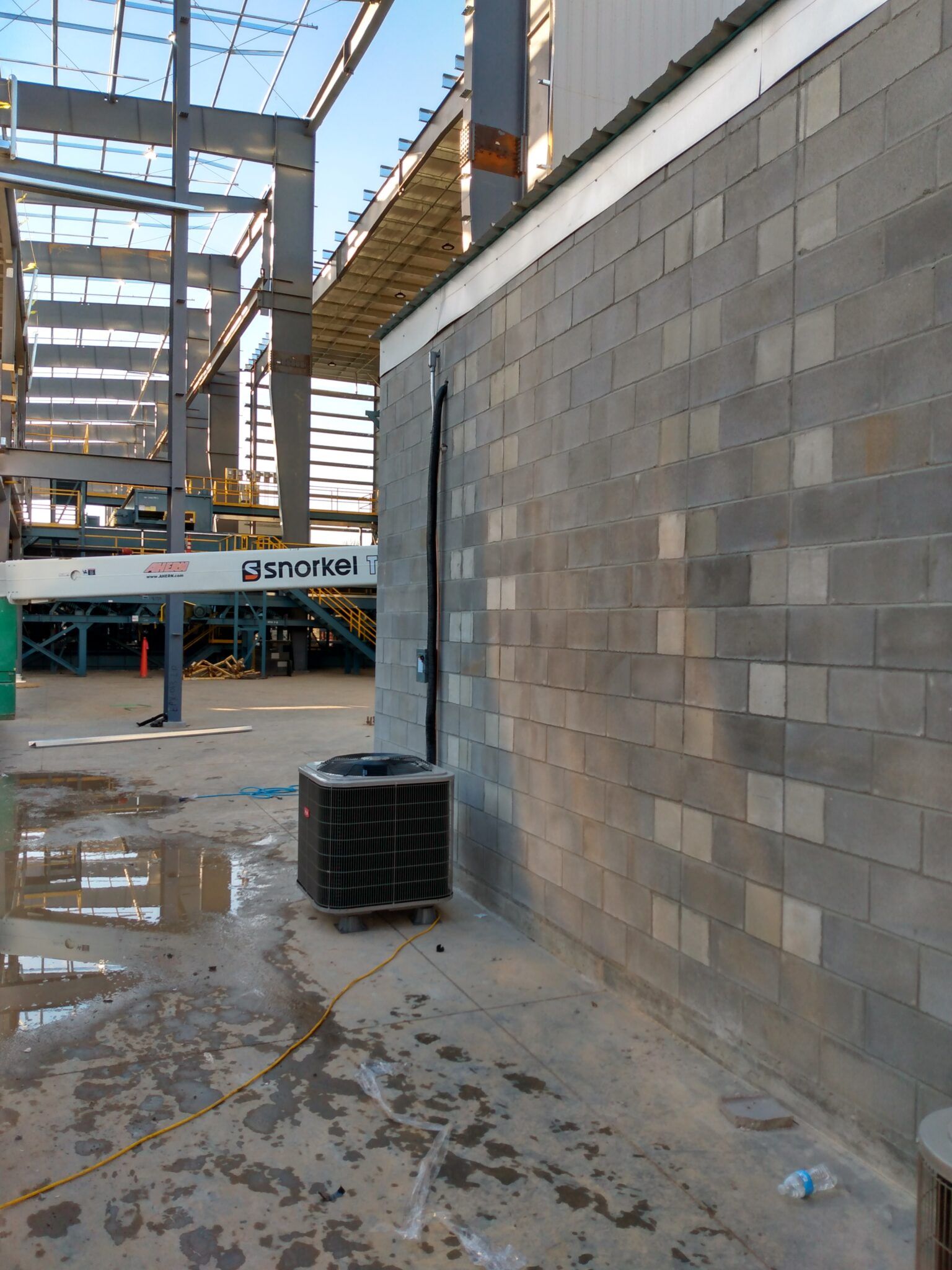 An air conditioner is sitting on the side of a building under construction