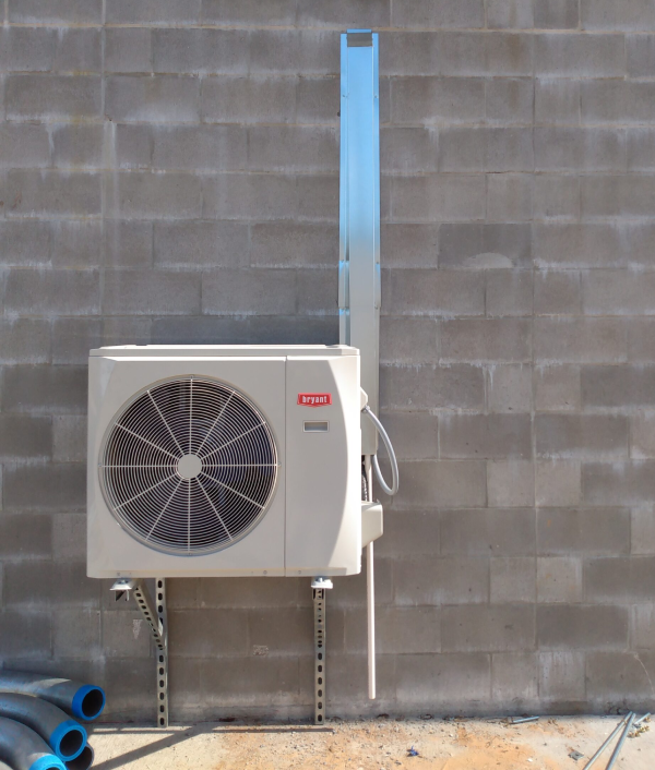 A white air conditioner is mounted to a brick wall