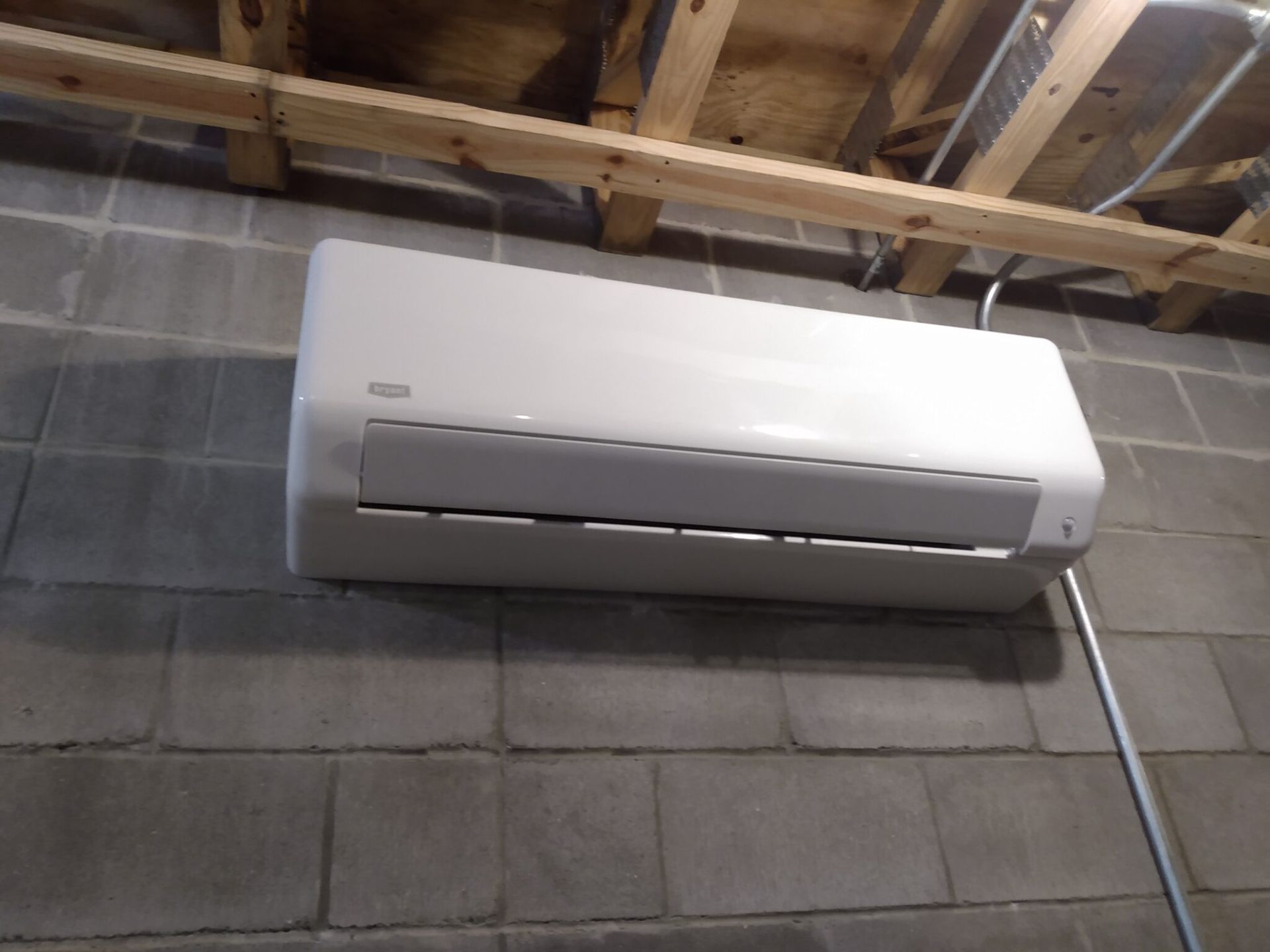 A white air conditioner is mounted on a brick wall