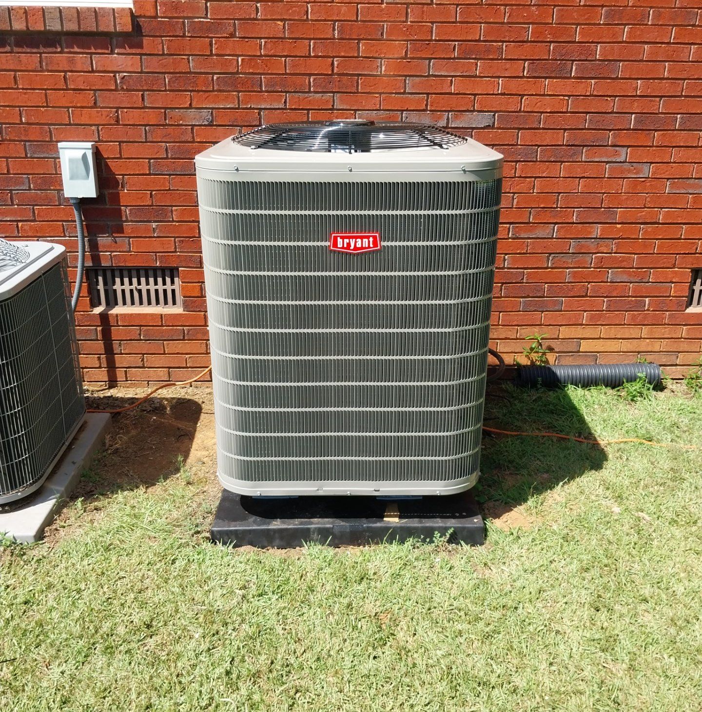 A joyer air conditioner is sitting in front of a brick building