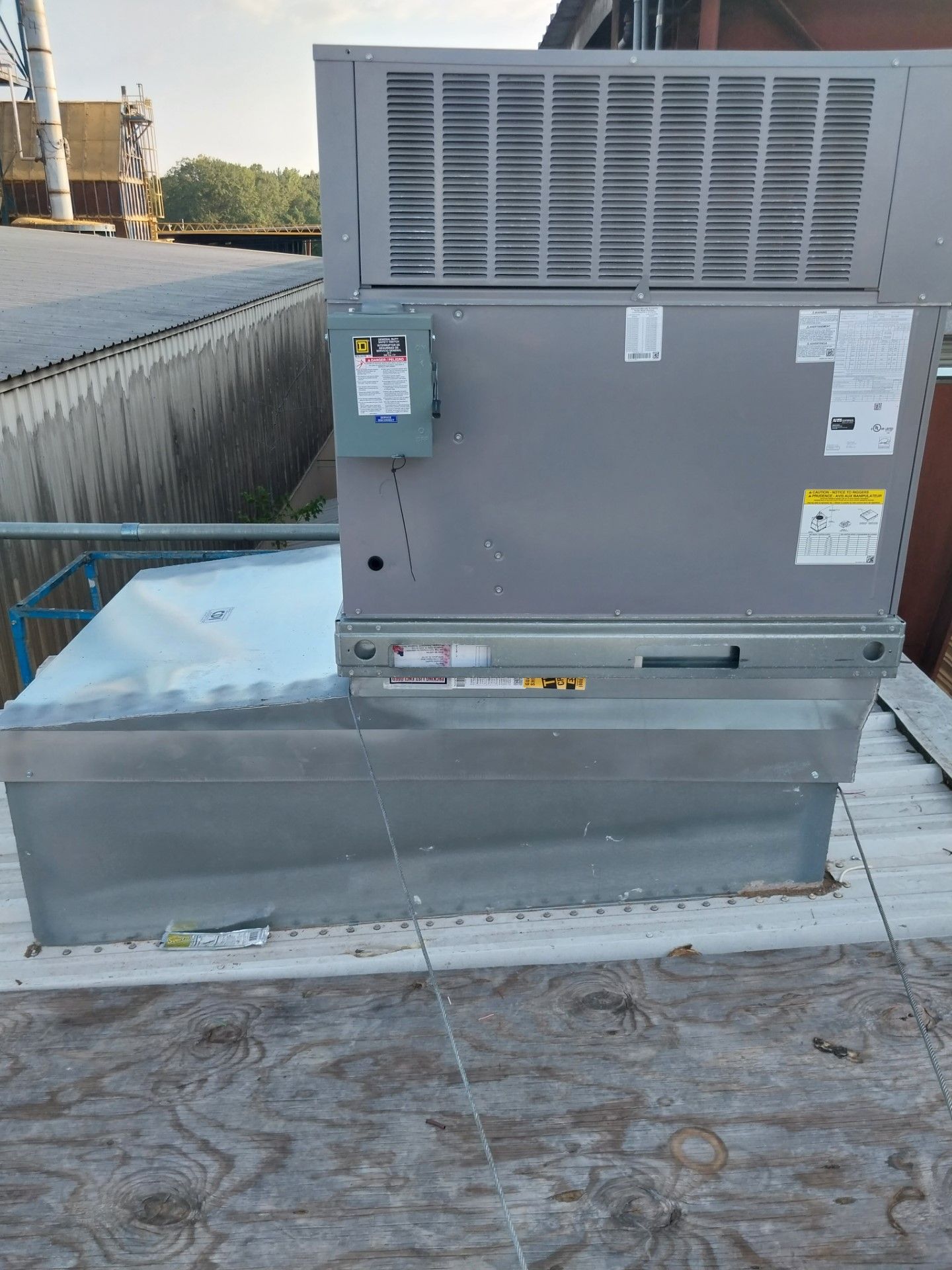 A large air conditioner is sitting on top of a wooden roof.