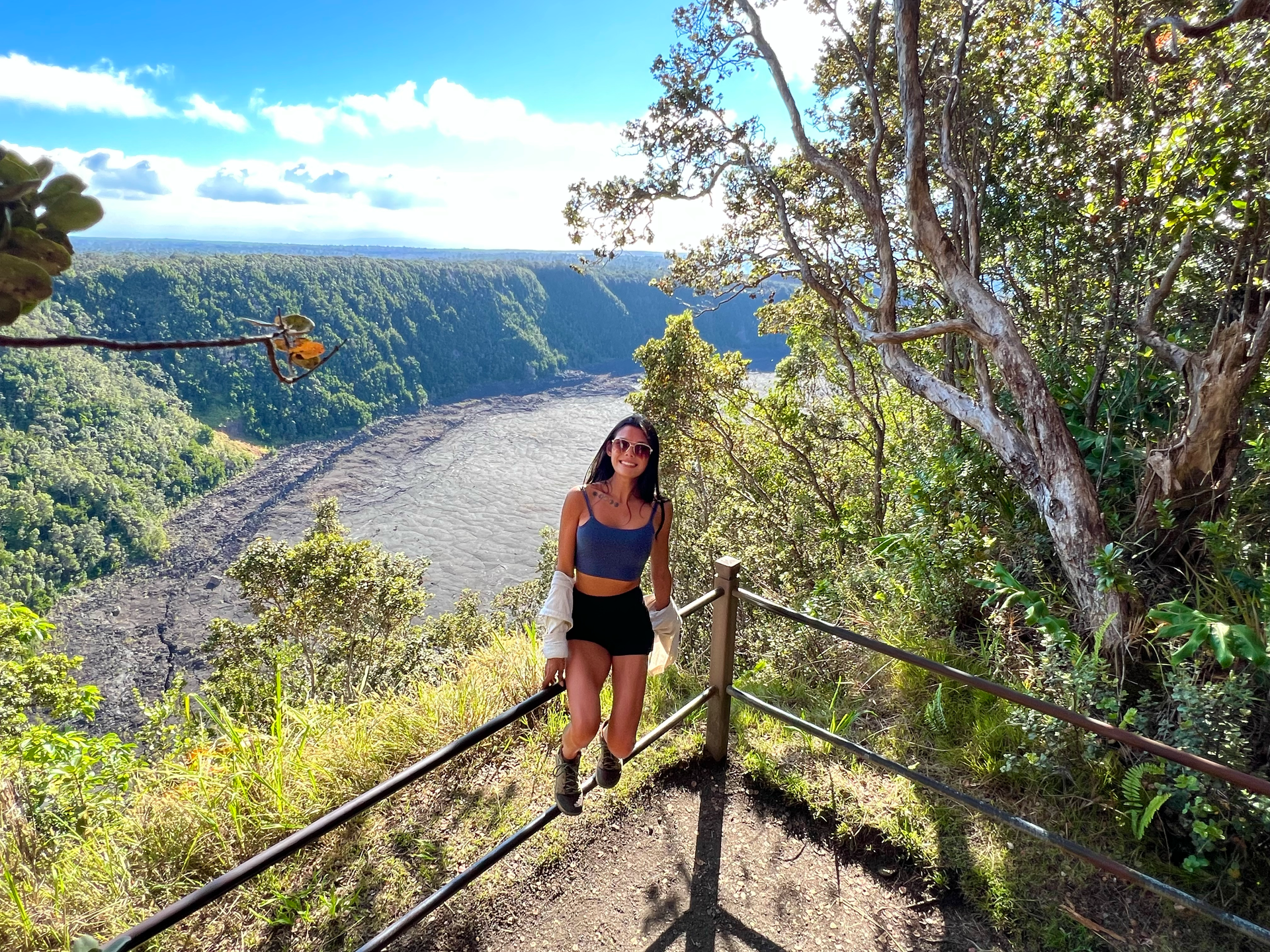 Becca is sitting on a fence overlooking a crater in Hawai'i Volcanoes National Park.