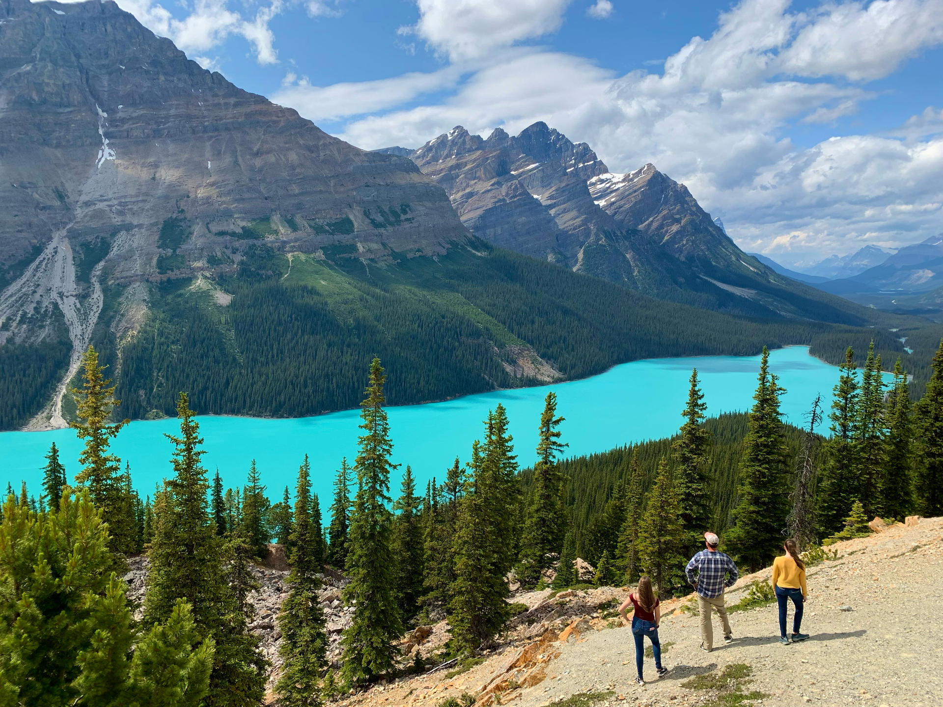 John and his daughters standing on top of a hill overlooking Peyto Lake surrounded by mountains.