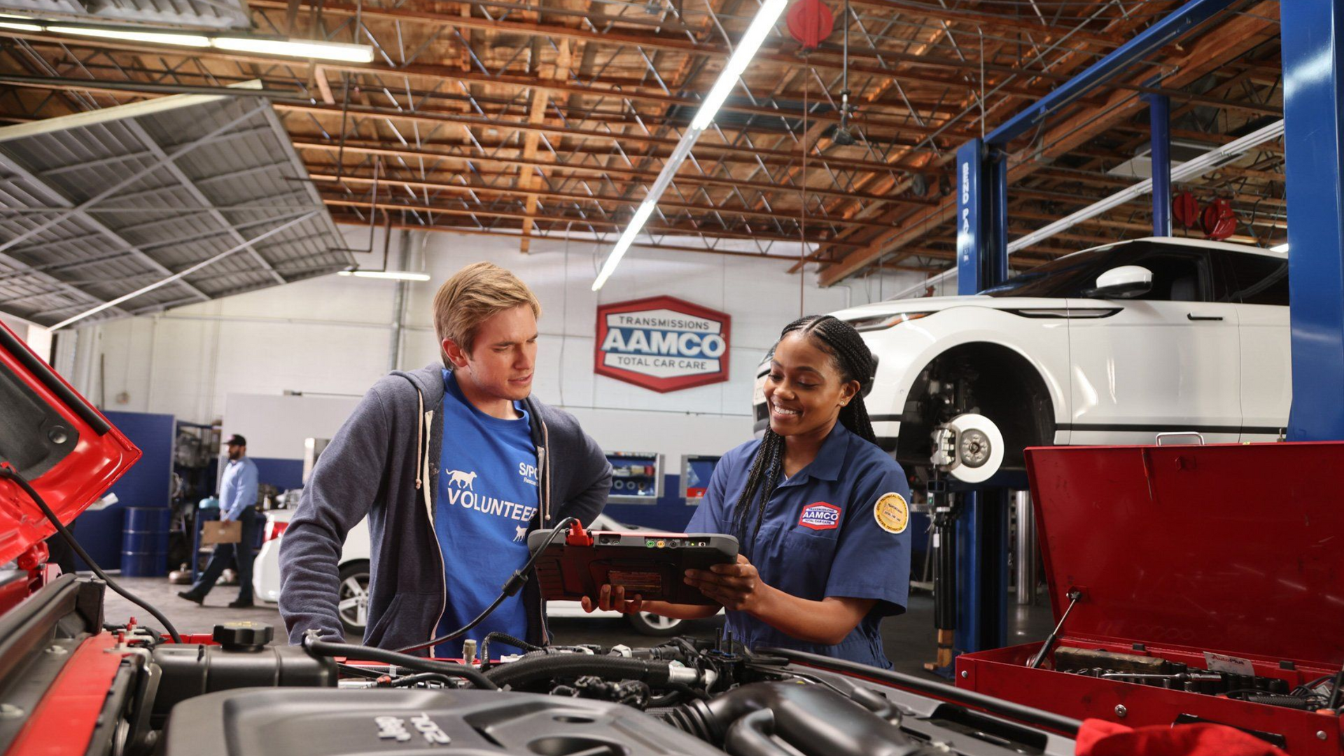 An aerial view of an AAMCO Transmissions & Total Car Care shop with multiple bays, adjacent to a residential area on a sunny day.