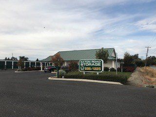 A storage facility with a green roof and a sign in front of it.