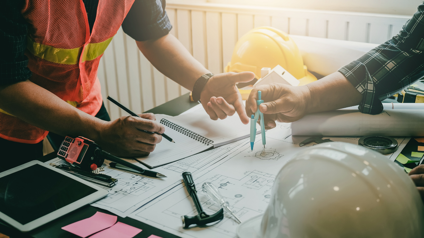 A construction worker wearing blue gloves uses a mallet to secure pavers into a sand base.