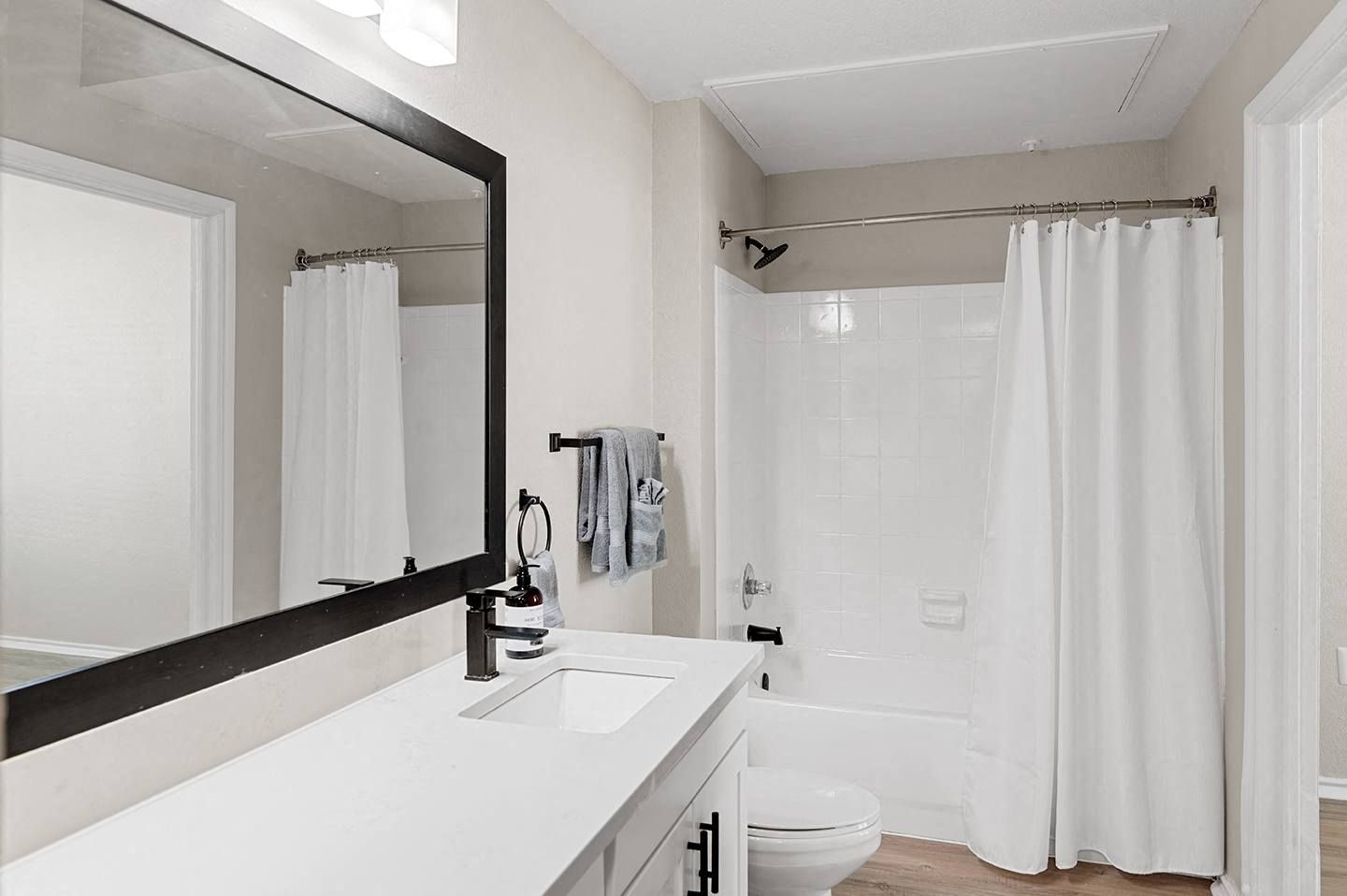 Modern bathroom with a mirror, sink, and bathtub at Villas of Vista Ridge in Lewisville, TX.