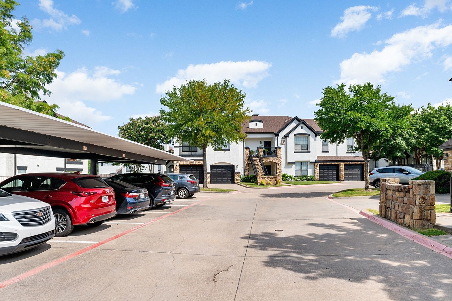 Exterior view of an apartment community with parking and landscaping at Villas of Vista Ridge in Lewisville, TX.