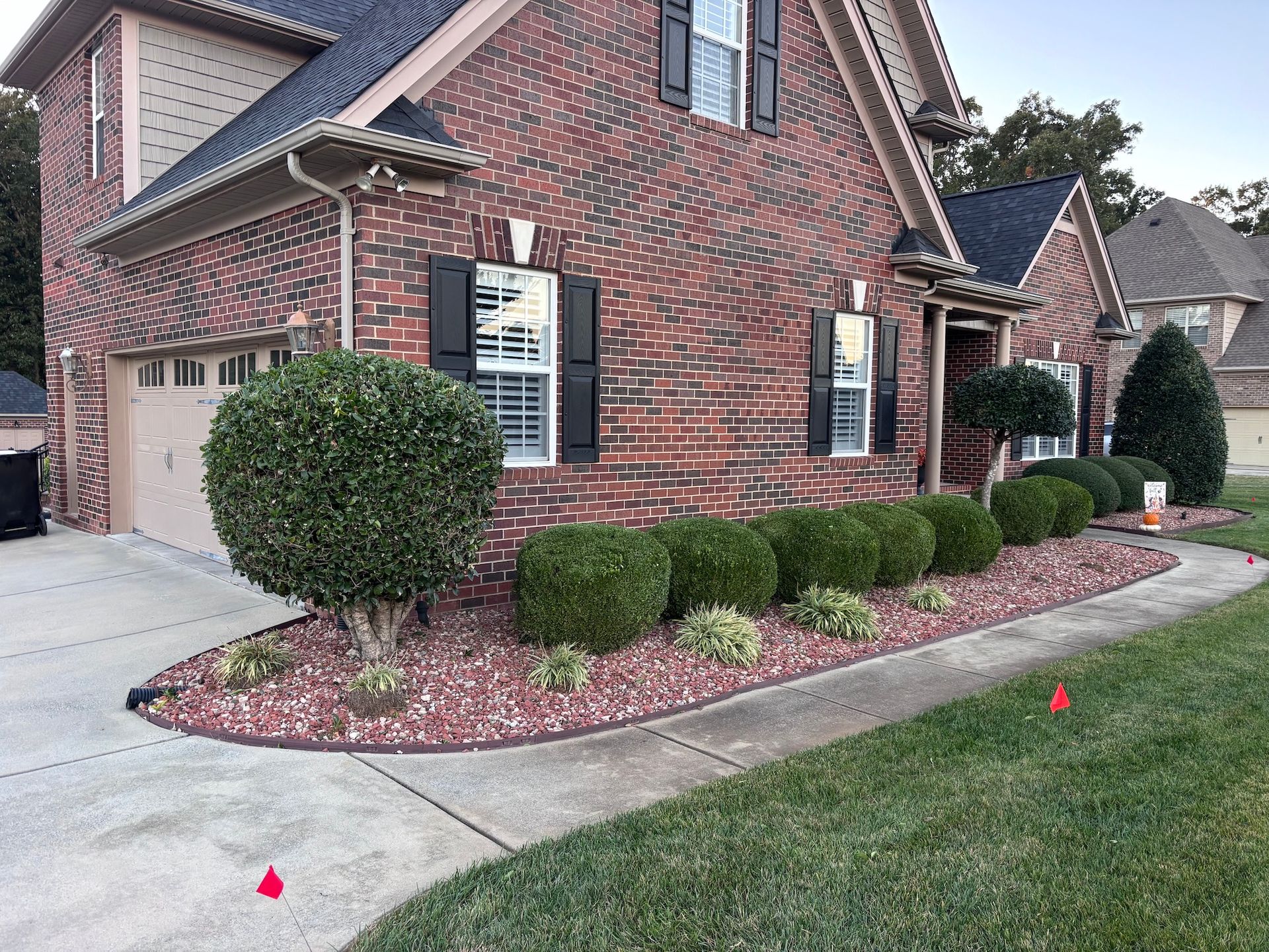 Red brick house with manicured landscaping, including bushes and a walkway.