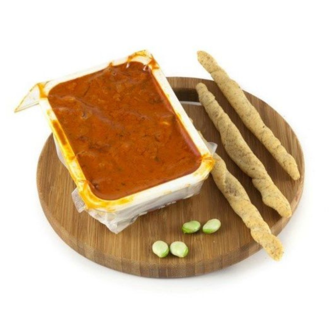 Un contenitore di salsa di pomodoro è su un tagliere di legno