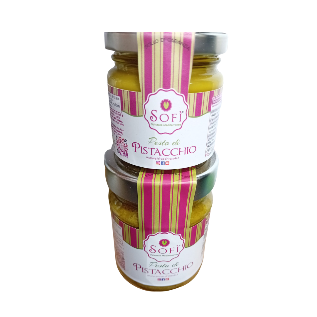 Due barattoli di crema spalmabile al pistacchio sono impilati uno sopra l'altro.