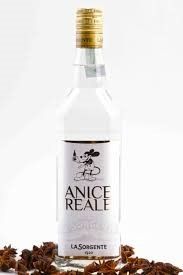 Una bottiglia di anice reale è appoggiata su un mucchio di anice stellato.