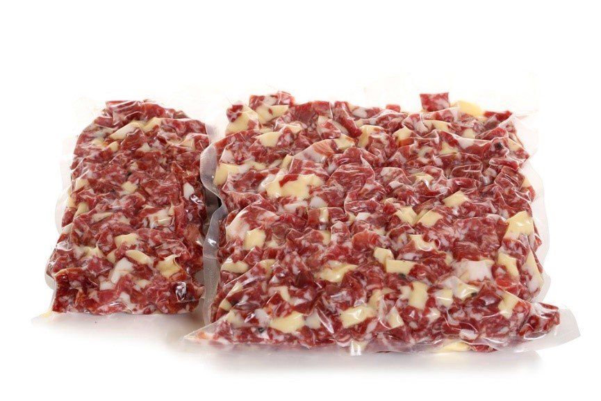 Due pezzi di carne macinata sono adagiati uno sopra l'altro su una superficie bianca.