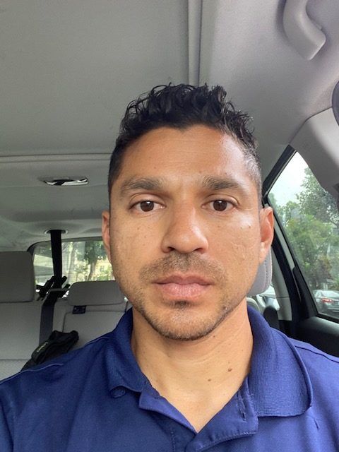 A man in a blue shirt is sitting in the back seat of a car.