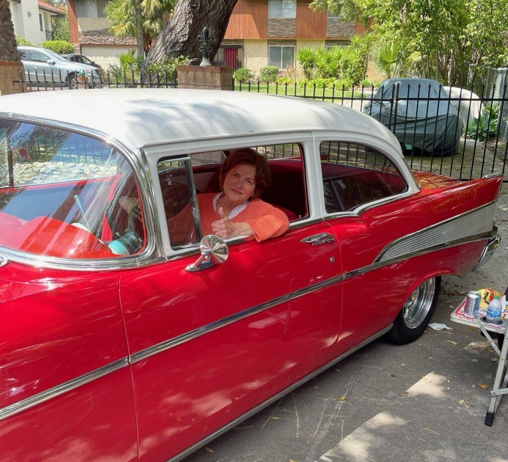 A woman is leaning out of the window of a red car