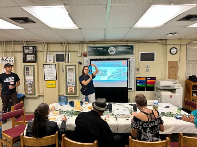 A woman is giving a presentation to a group of people in a room.