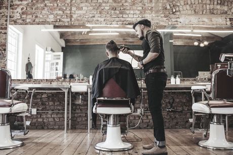 A man is getting his hair cut by a barber in a barber shop.