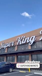 A car is parked in front of a super king supermarket.