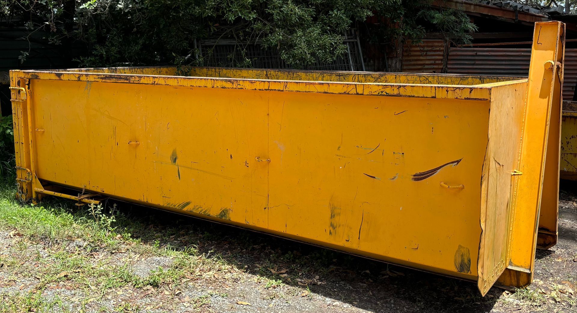 A Yellow Skip Bin Infront Of A Fence — Bin Hire in Maryborough, QLD