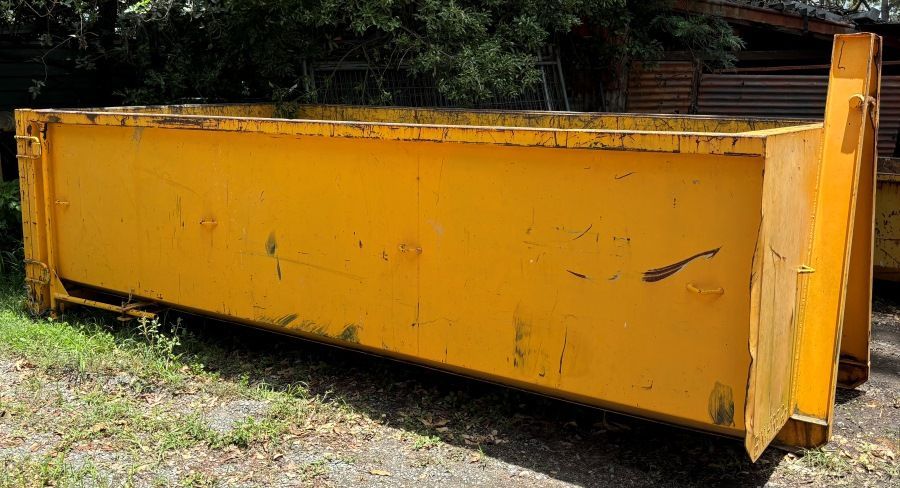 A Large Yellow Dumpster is Sitting in the Grass in a Yard — Bin Hire in Maryborough, QLD