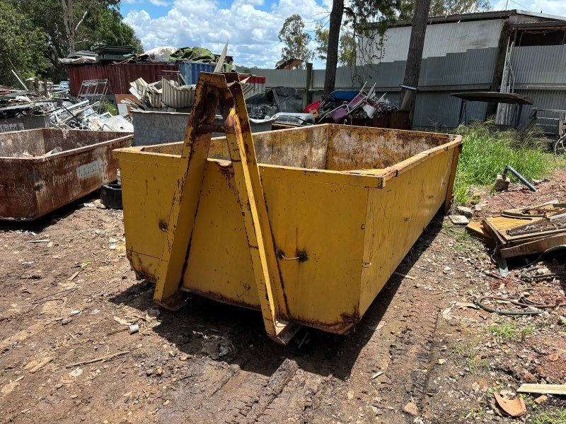 A Large Yellow Dumpster is Sitting on Top of a Dirt Field — Bin Hire in Maryborough, QLD
