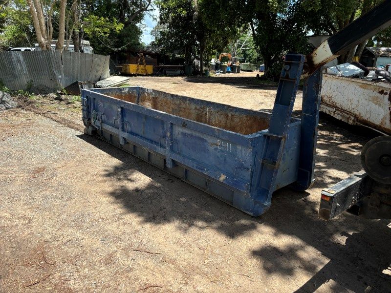 A Blue Dumpster is Parked in a Dirt Lot Next to a Truck — Bin Hire in Hervey Bay, QLD