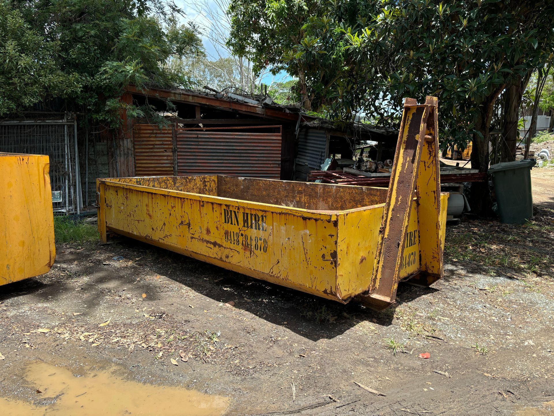 A Yellow Skip Bin In A Garden — Bin Hire in Maryborough, QLD