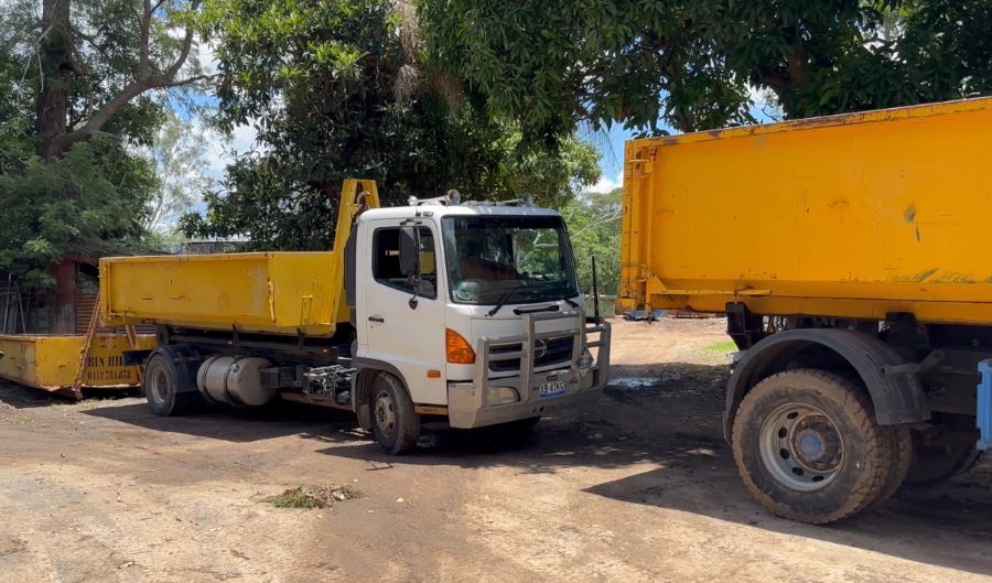 Two Dump Trucks Are Parked Next to Each Other in a Dirt Lot — Bin Hire in Hervey Bay, QLD