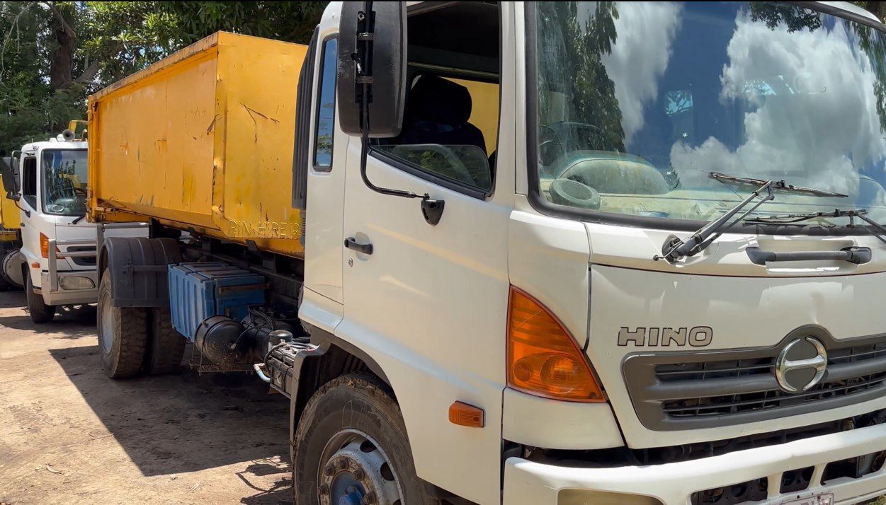 A White Dump Truck is Parked Next to a Yellow Dump Truck — Bin Hire in Maryborough, QLD