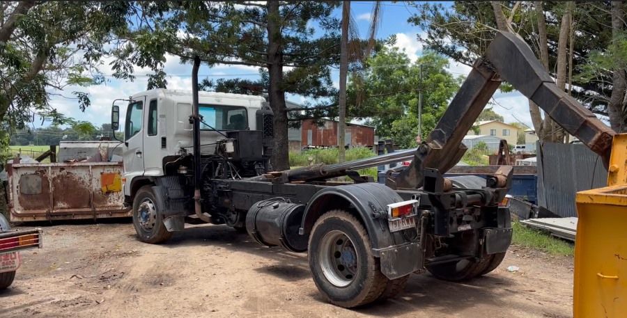 A Dump Truck With a Crane Attached to It is Parked in a Dirt Lot — Bin Hire in Maryborough, QLD