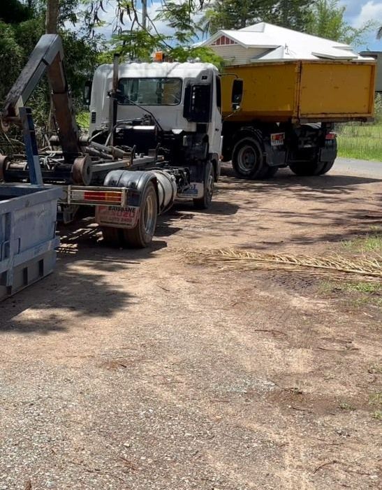 A Yellow Dumpster Is Sitting In Front Of A Brick House — Bin Hire In Maryborough, QLD
