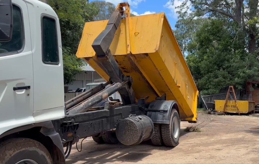 A Dump Truck is Being Loaded With a Yellow Dumpster — Bin Hire in Hervey Bay, QLD