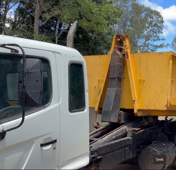 A White Truck is Parked Next to a Yellow Dumpster — Bin Hire in Maryborough, QLD