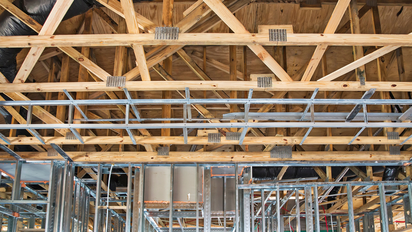 Interior of a building under construction with exposed wooden roof trusses and metal framing