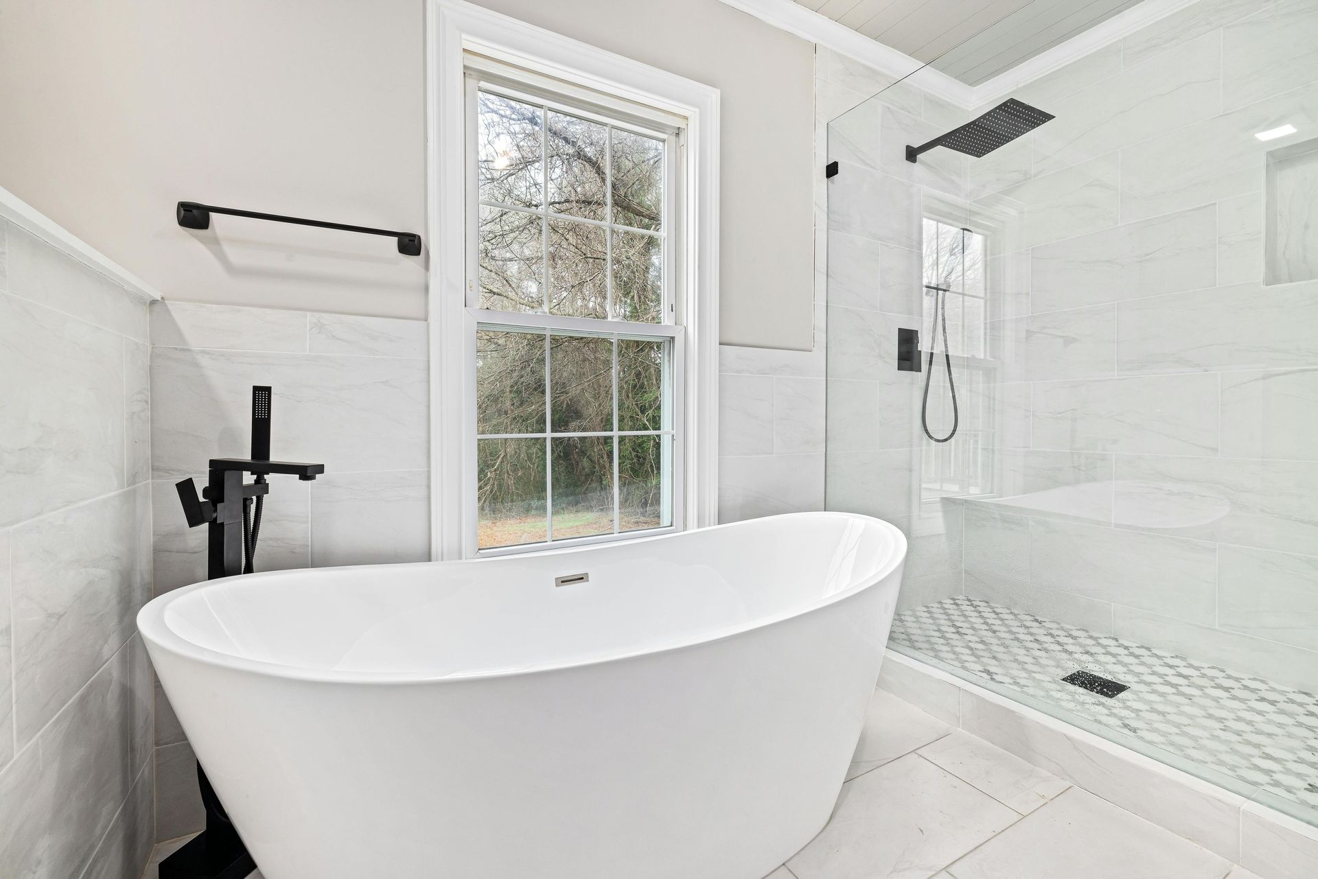 Bright white bathroom with a freestanding tub, walk-in shower, and window.