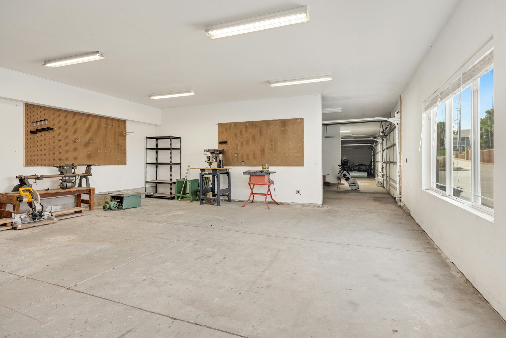 Empty workshop space with concrete floor, white walls, and large windows.