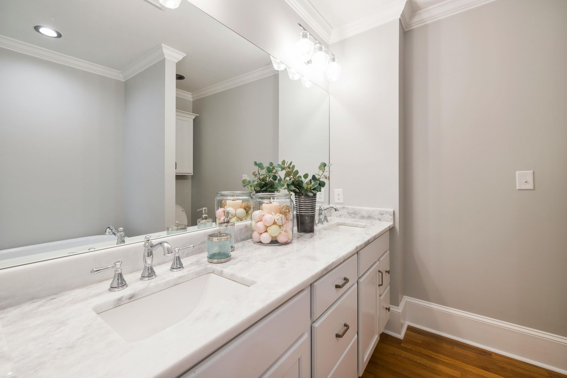 Bright bathroom vanity with double mirrors, white countertop, and floral decor against gray walls.