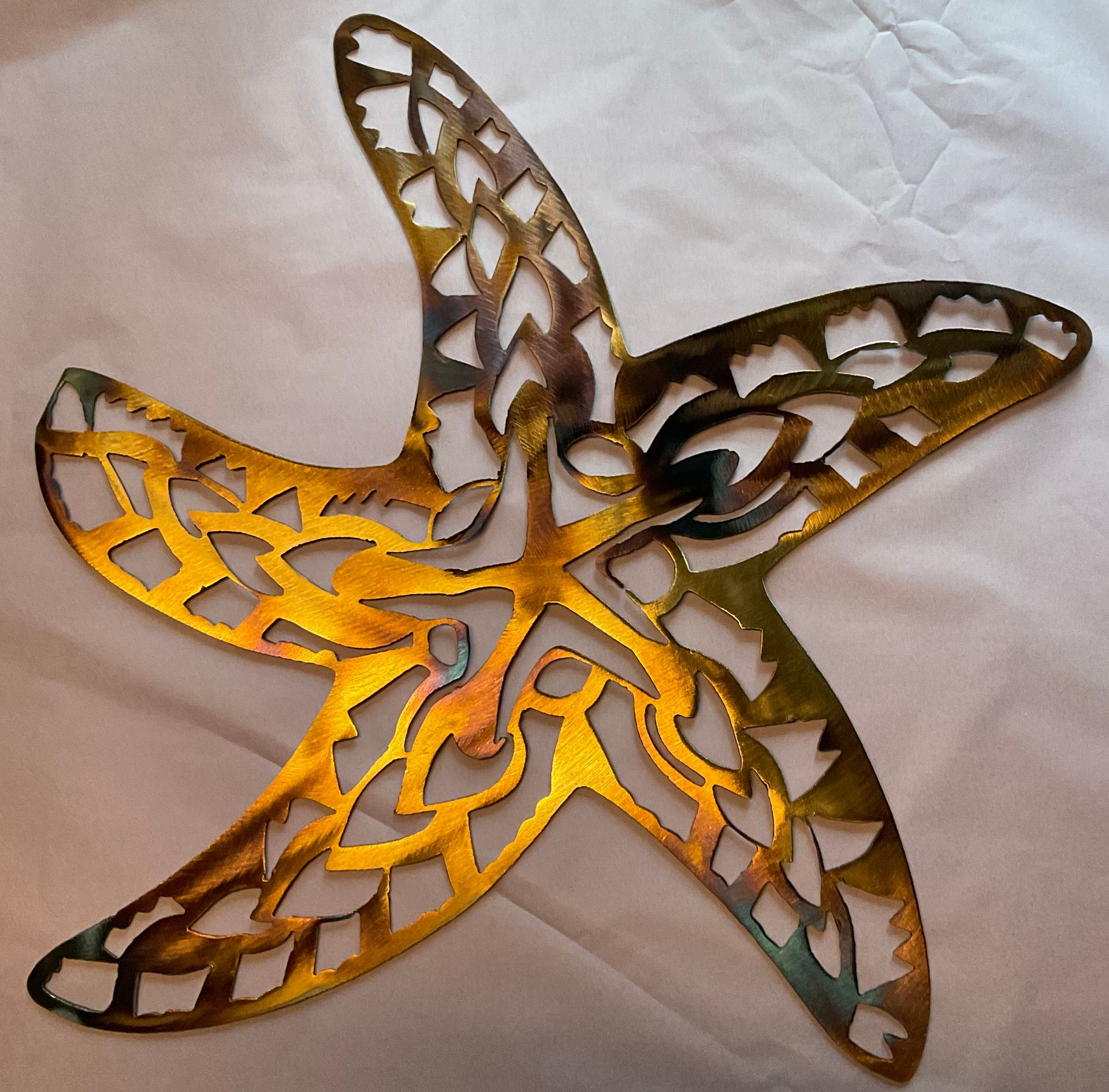 Metal starfish wall art with cutout design; yellow and bronze tones.
