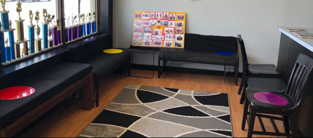 A waiting room with a rug and chairs and trophies on the wall