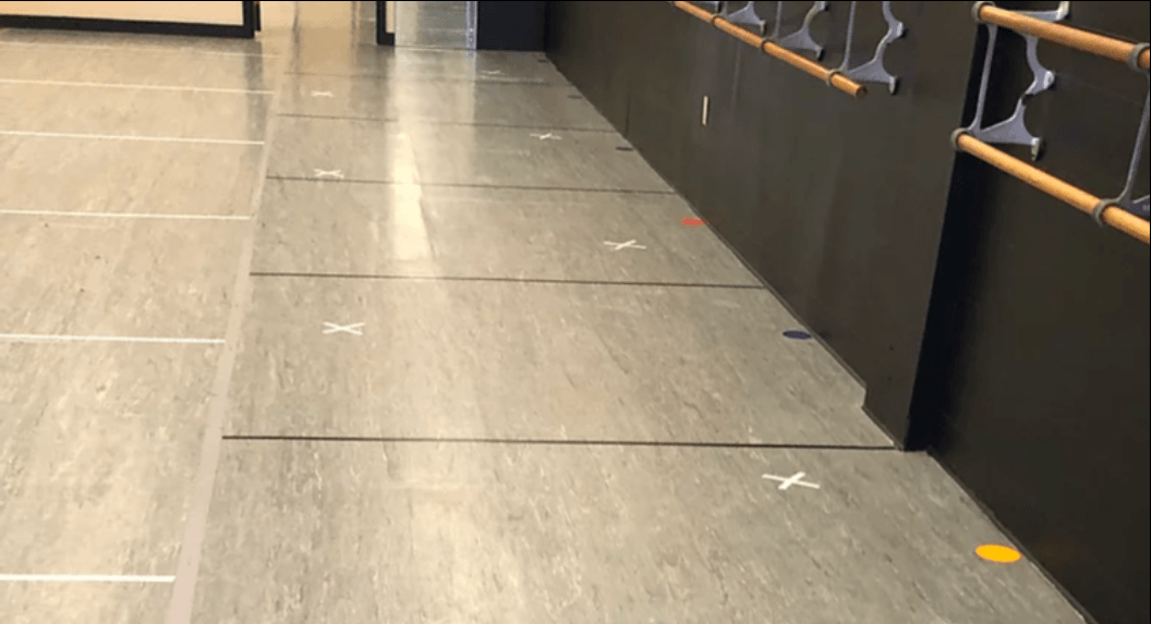 A hallway with a row of ballet barres on the wall.