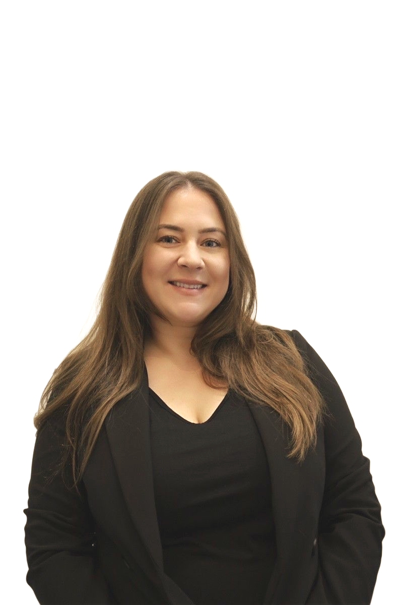 Woman with long brown hair, wearing a black blazer and top, smiling in front of a white wall.