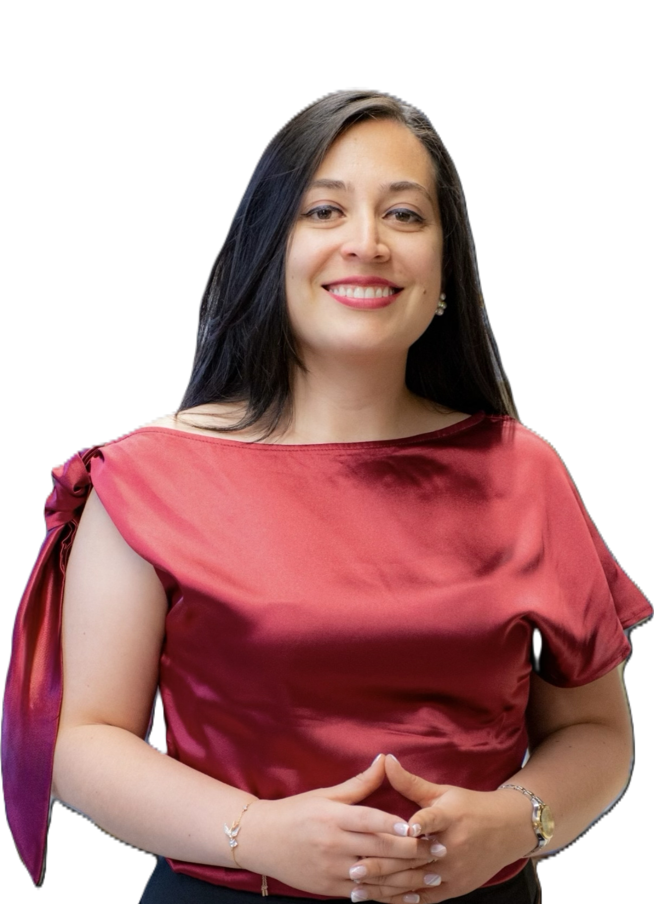 Woman with dark hair, wearing a red top and black pants, smiling with hands clasped.