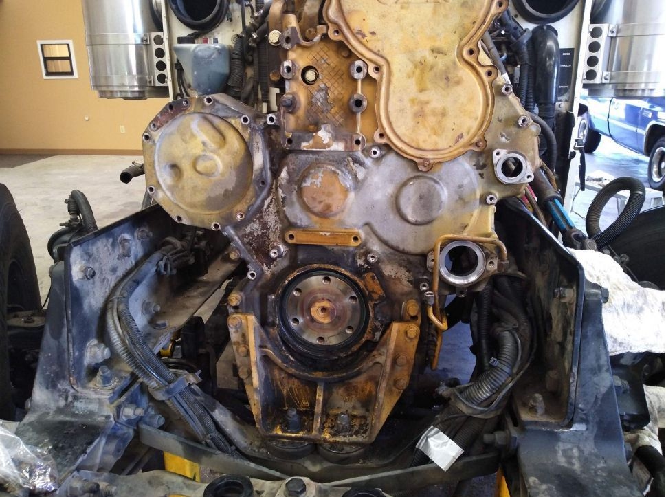 A large engine is being dismantled in a garage.