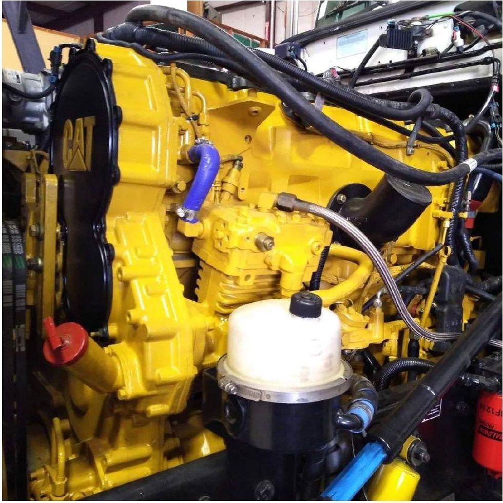 A yellow cat engine with blue hoses coming out of it
