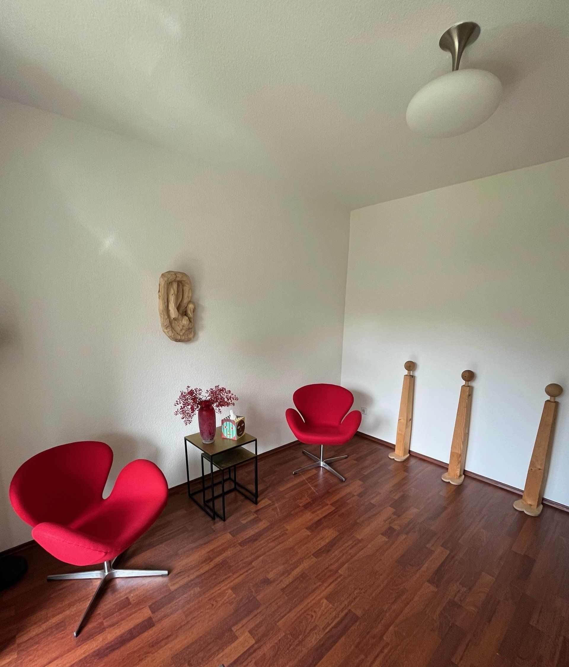 Ein Wohnzimmer mit zwei roten Stühlen und einem Tisch