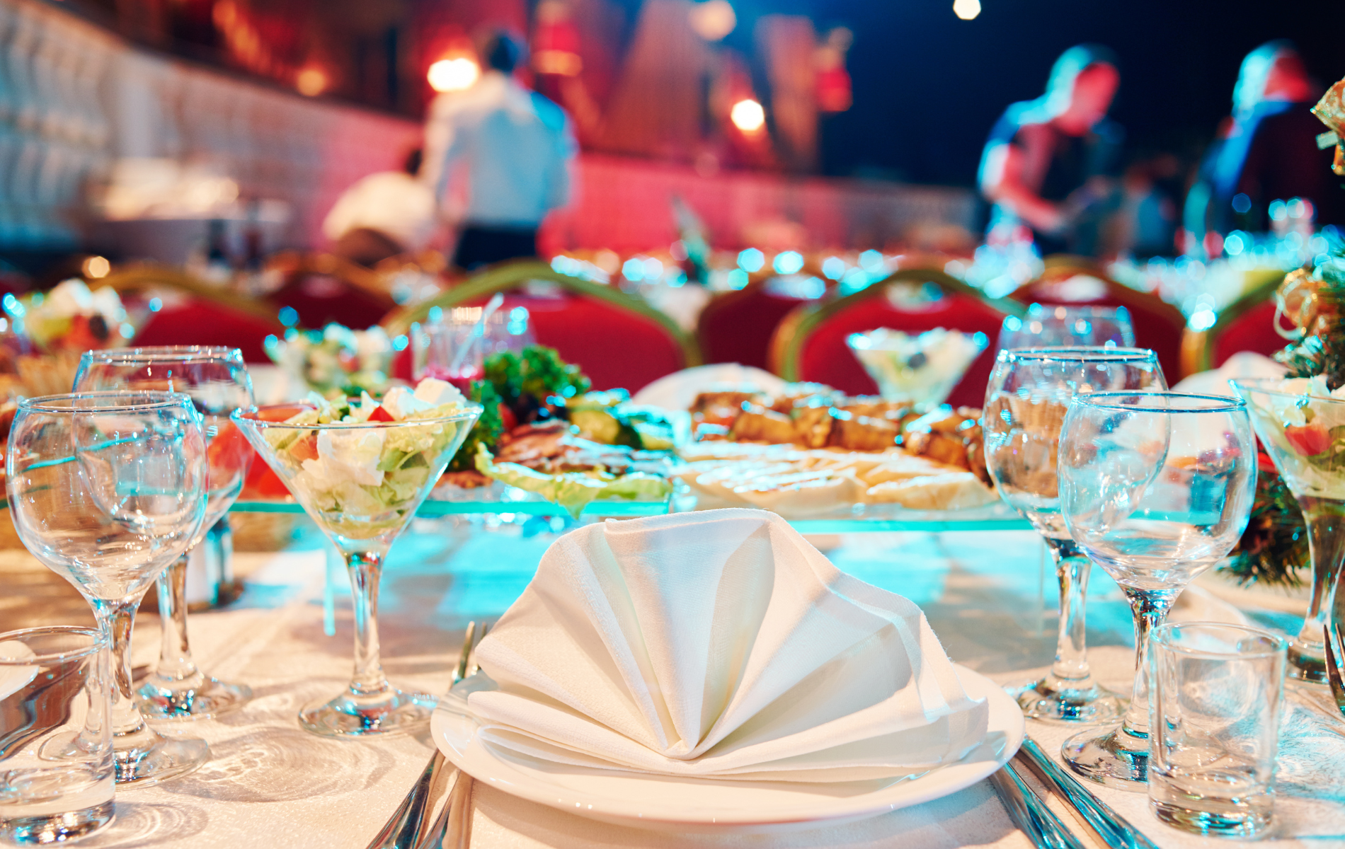 A table set for a banquet with plates , wine glasses , and napkins.