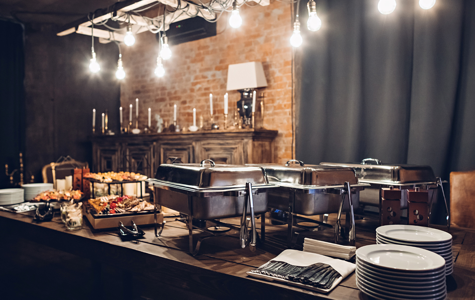 A long table with plates and trays of food on it.